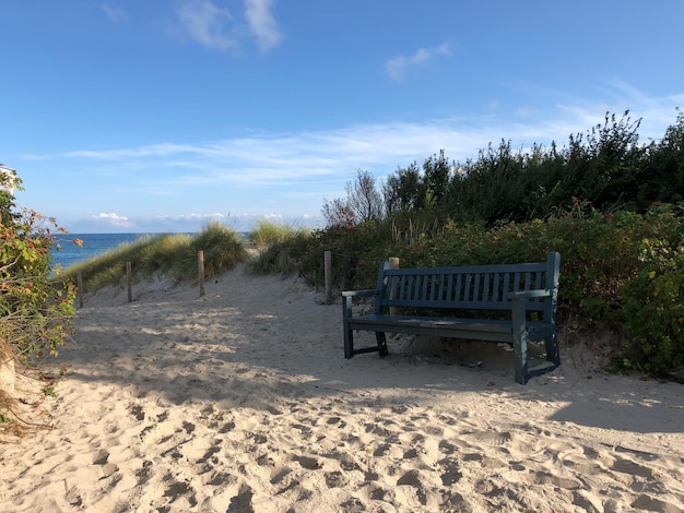 Leere Bank am Strand gegen den Himmel