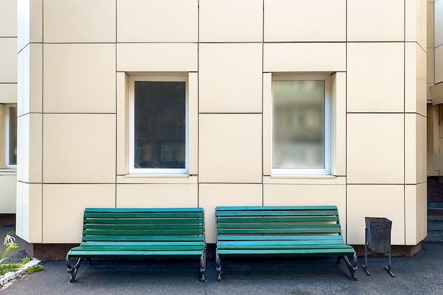 Leere Bank gegen klassische Fassade mit großen weißen Fenstern im Hinterhof des Gebäudes