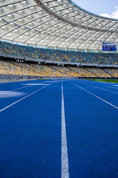 Leere blaue Laufstrecke im Olympiastadion vor dem Hintergrund leerer Tribünen