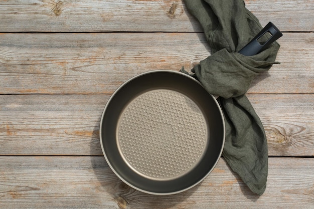 Leere Bratpfanne auf einem Holztisch, der Lebensmittelkonzept kocht