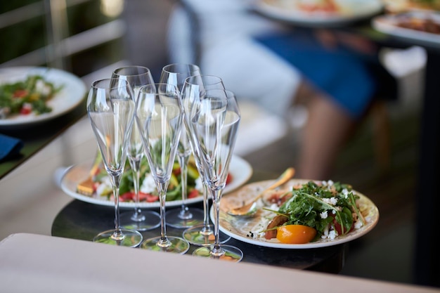 leere champagnergläser und teller mit essen auf dem tisch, nahaufnahme