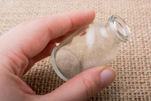 Leere Flasche in der Hand auf einer Leinenleinwand