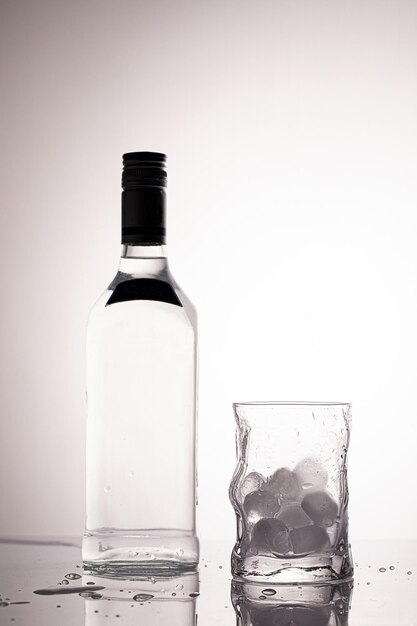 Foto leere flasche und glas mit eiswürfeln in monochromatischer farbpalette