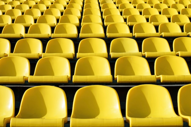 Leere gelbe Plastiksitze im Stadion, Sportarena mit offener Tür.