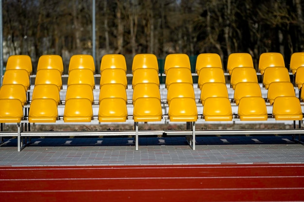 Leere gelbe Plastiksitze in der Sportarena des Stadions mit offener Tür