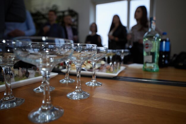 Foto leere gläser für cocktails und snacks stehen im vordergrund auf einem holztisch vor dem hintergrund von menschen