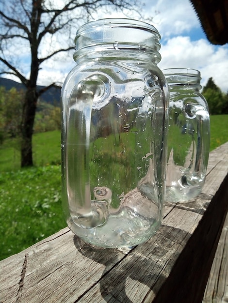 Leere Gläser mit Griffen auf Holzveranda Sommergarten Hintergrund Ferienlandschaft