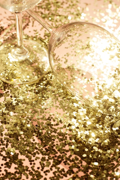 Foto leere glasbecher für champagner in goldenem konfetti auf dem tisch. festlicher hintergrund. party-konzept.