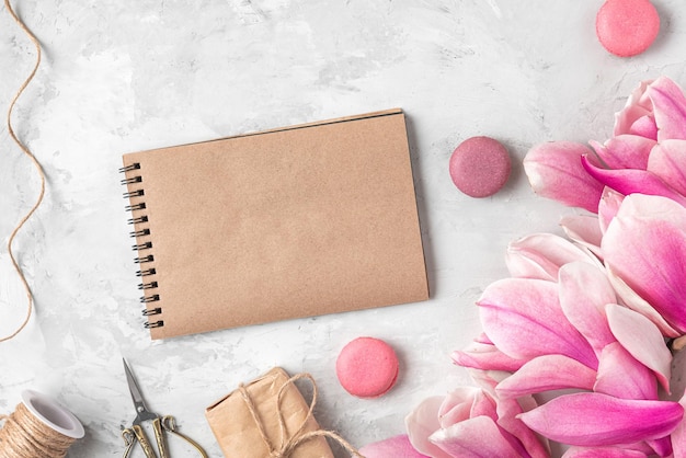 Leere Grußkarte mit Geschenkbox mit Magnolienblüten und Macarons Hochzeitshintergrund Mock-up Flach legen
