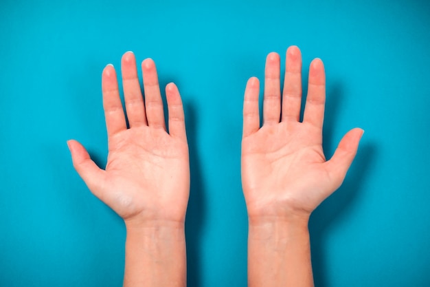 Leere Handflächen der Frau auf blauem Hintergrund. Nahaufnahme.