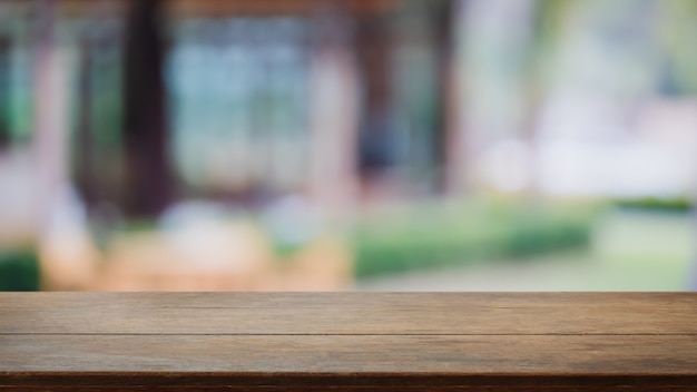 Leere hölzerne Tischplatte und verwischen Sie Glasfenster außen im Freien Restaurant Banner verspotten abstrakten Hintergrund