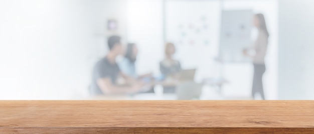 Leere hölzerne Tischplatte und verwischte Bokeh-Leute, die im Hintergrund des Büroinnenraumbanners arbeiten.