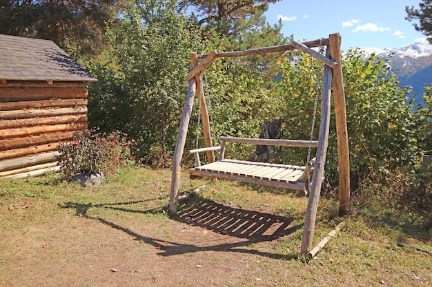 Leere Holzschaukel neben der Blockhütte