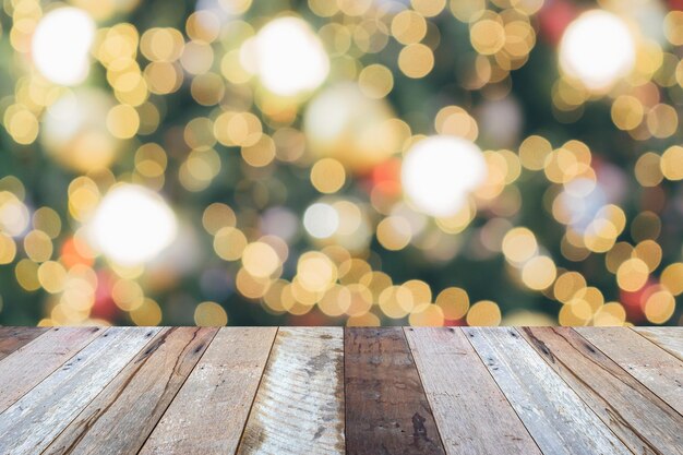 Leere Holztischplatte mit verschwommenem Weihnachtsbaum mit hellem Bokeh-Hintergrund