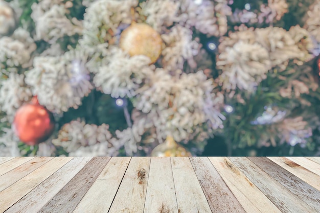 Leere Holztischplatte mit verschwommenem Weihnachtsbaum mit hellem Bokeh-Hintergrund