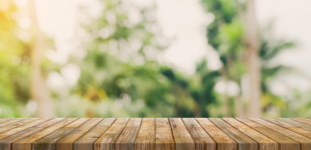 Leere Holztischplatte und abstraktes unscharfes helles Bokeh und unscharfer Hintergrund von Gartenbäumen im Sonnenlicht Produktanzeigevorlage mit Kopierraum