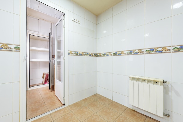 Leere Küche mit weiß gefliesten Wänden mit Obsträndern und hellbraunen Fliesenböden