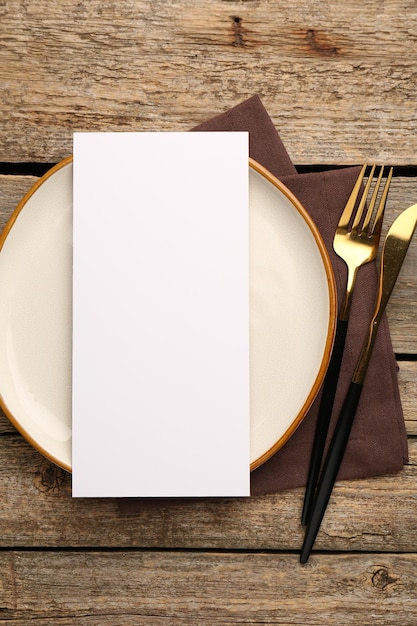 Leere Menü, Besteck, Teller und Serviette auf einem Holztisch, Mockup für das Design