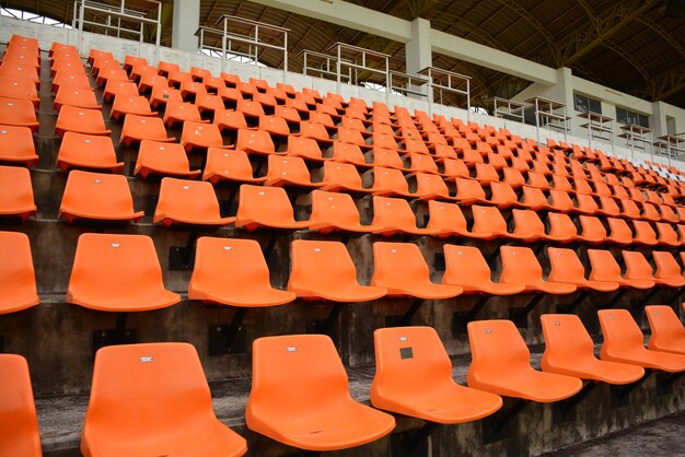 Leere orange Farbstühle auf Stadion im Schritt.