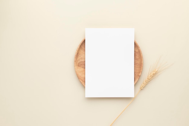 Leere Papierkarten, Mockup mit Weizen auf einer Holzplatte, beiger Hintergrund, minimale beige Arbeitsplatzzusammensetzung, flache Lage, Mockup