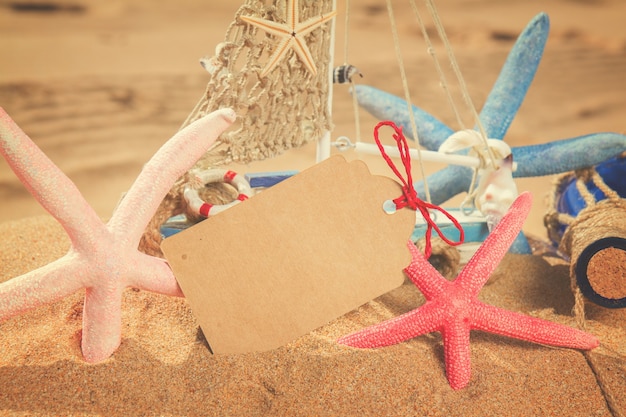 Leere Papiernotiz mit Seesternrahmen am Sandstrand, Retro-Ton