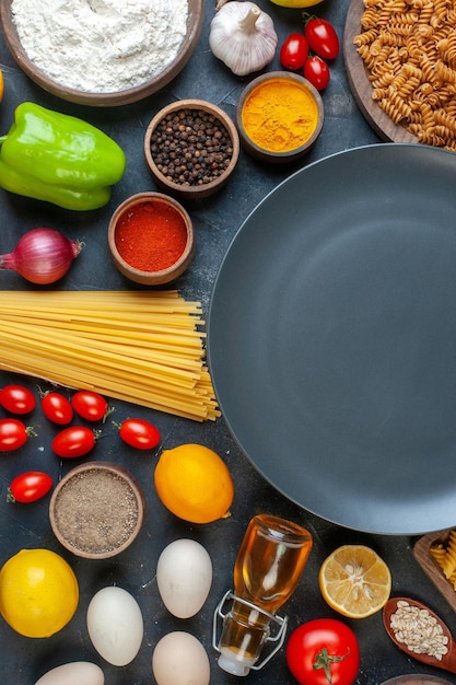 Leere Platte der Draufsicht um Eier, Tomaten, Gewürze und italienische Pasta auf dunklem Hintergrund, Farbe, Gemüse, Küche, Küche, Lebensmittel, Obst