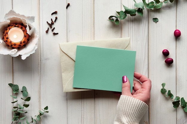 Leere Postkarte in der Hand Winterurlaub Grußkarte Modell Eukalyptus Teelicht in Pomander Ball