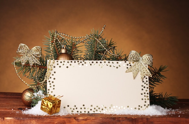 Leere Postkarte, Weihnachtskugeln und Tannenbaum auf Holztisch