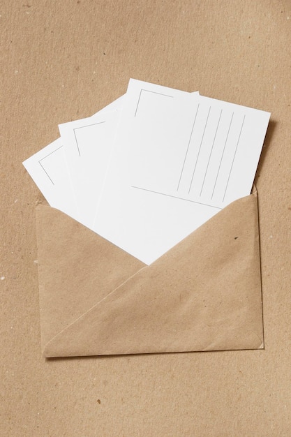 Foto leere postkarten im kraftpapierumschlag auf kartonhintergrund