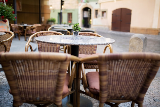 Leere Rattanstühle und Tische vor einem Straßenrestaurant in der Stadt