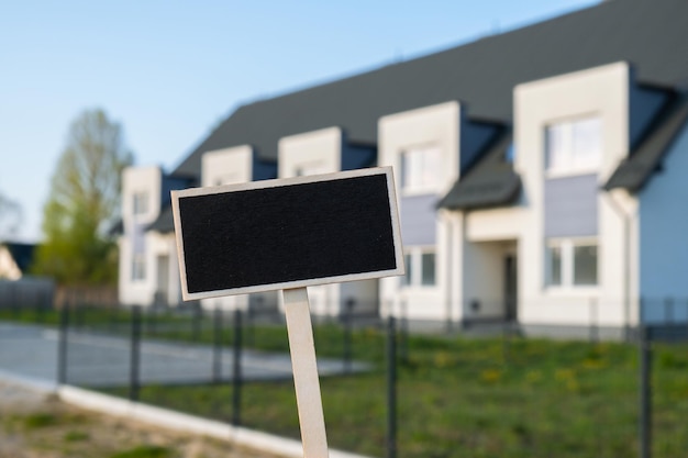 Leere schwarze Plakatwand gegen Wohnung Einfamilienhaus Leere Mockup-Vorlage Tafeletikett bei Townhome Platzbanner für Ihren Text kopieren Mehrfamilienhaus Konzept des Mietpreises Hauskaufhaus