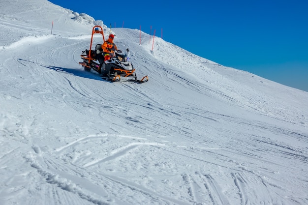 Leere skipiste bei sonnigem wetter. bergrettung auf einem schneemobil