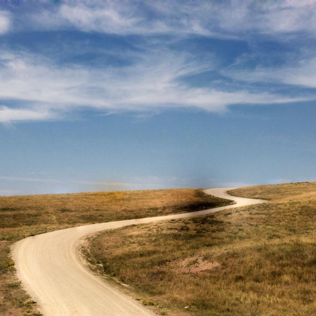 Leere Straße auf einem grasbewachsenen Feld gegen den Himmel