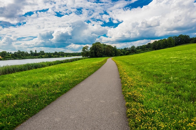 Leere Straße durch Grasfeld gegen bewölkten Himmel