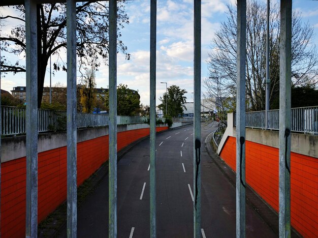 Leere Straße gegen den Himmel durch den Zaun gesehen