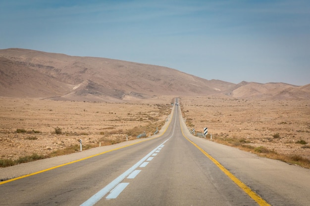 Leere Straße irgendwo zwischen Felsen und Sand in der Negev-Wüste in der Nähe von Mitzpe Ramon in Israel