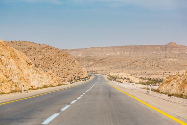 Leere Straße irgendwo zwischen Felsen und Sand in der Negev-Wüste in der Nähe von Mitzpe Ramon in Israel