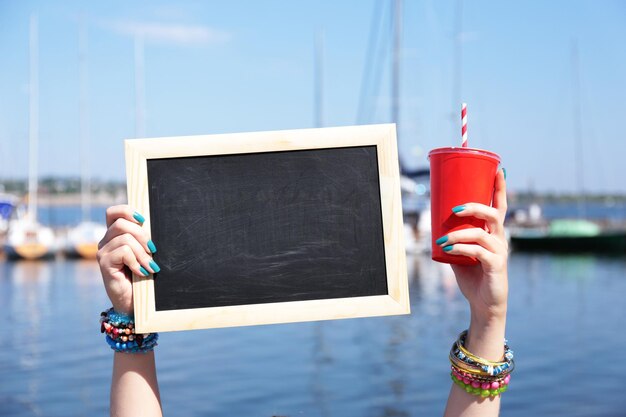 Leere Tafel in weiblicher Hand auf Strandhintergrund