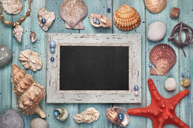 Leere Tafel mit Muscheln, Steinen, Seil und Stern fischen auf Blau