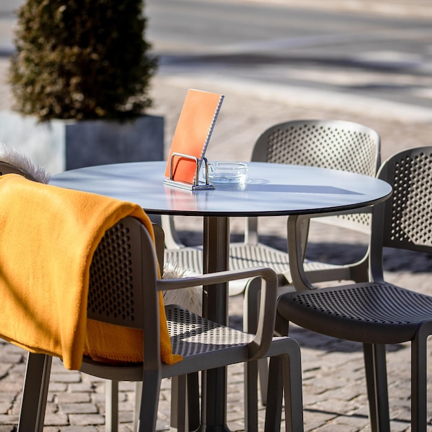 Leere Tische draußen zwischen den Mittagsstunden entlang einer gepflasterten Gasse in einer europäischen Stadt eine Veranda ein Café