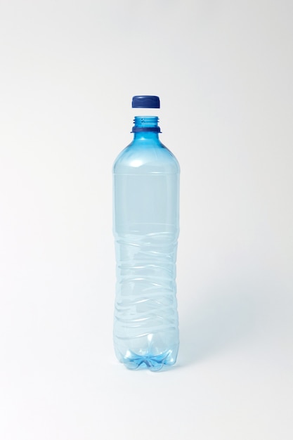 Leere transparente Plastikflasche mit blauer Kappe auf hellgrauem Hintergrund, Kopienraum. .