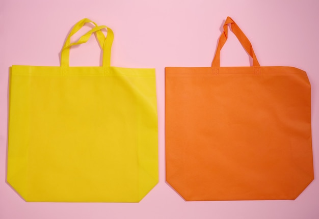 Leere umweltfreundliche Leinentragetasche aus Viskose für das Branding auf rosa Hintergrund. Durchsichtige wiederverwendbare Tasche für Lebensmittel, Mock-up. Flach legen