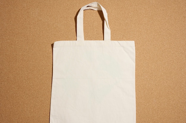 Leere umweltfreundliche Leinentragetasche beige für das Branding auf braunem Hintergrund. Durchsichtige wiederverwendbare Tasche für Lebensmittel, Mock-up. Flach legen