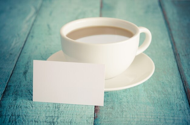 Leere Visitenkarte und Tasse Kaffee auf blauem Holztisch.