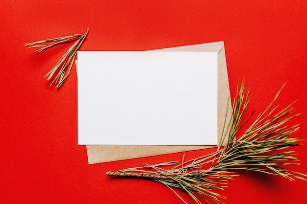 Leere Weihnachtsnotiz mit Tannenzweig auf rotem isoliertem Hintergrund. Neujahrskonzept