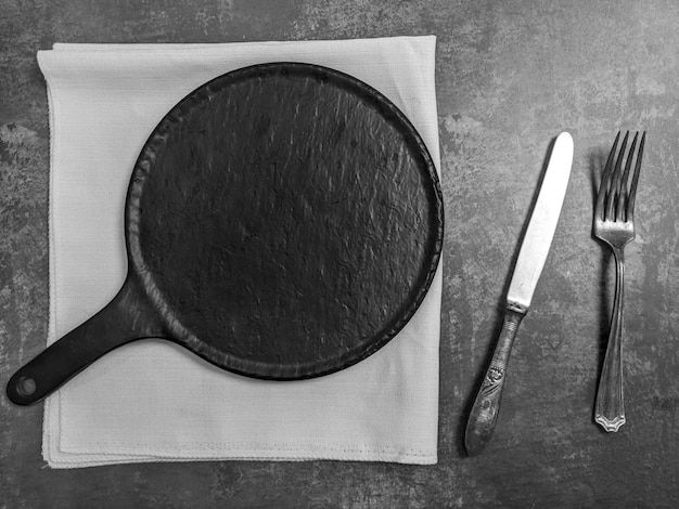 Leere weiße keramische Platte mit Messer und Gabel auf grauem Steinbetontabellenhintergrund. Kopieren Sie Platz. Menü-Rezept-Konzept