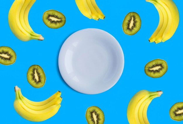 Foto leere weiße platte für den text banane und kiwi auf blauem hintergrund top-view kopierraum