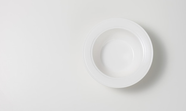 leere weiße runde keramische Suppenplatte auf einem weißen Tisch