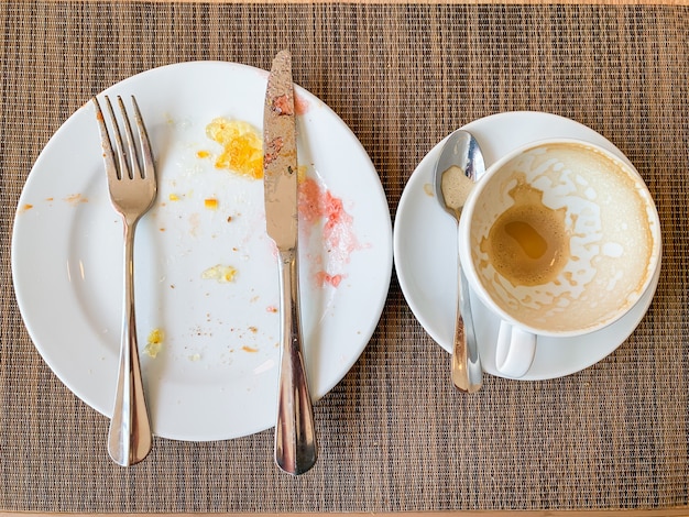 Leere weiße Teller und Kaffeetasse mit nach dem Frühstück auf Holztisch.