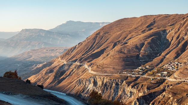 Leere zeitgenössische Autobahn verläuft entlang brauner felsiger Hänge des hohen alten Berges gegen den klaren blauen Himmel am sonnigen Herbsttag-Luftpanorama